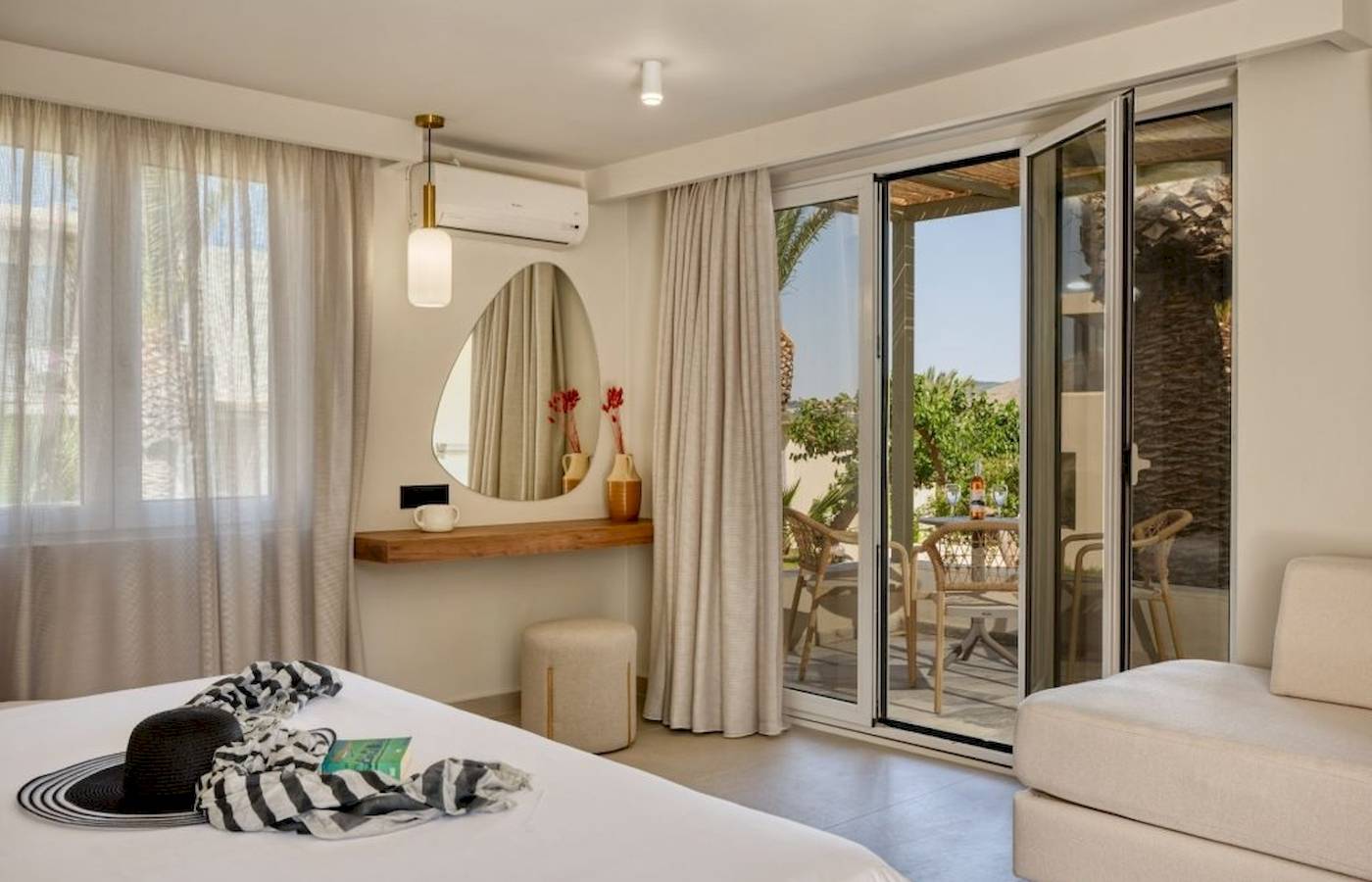 Innenansicht eines Zimmers im Georgioupolis Resort Aquapark & SPA mit großem Bett, offenem Balkon und Gartenblick.