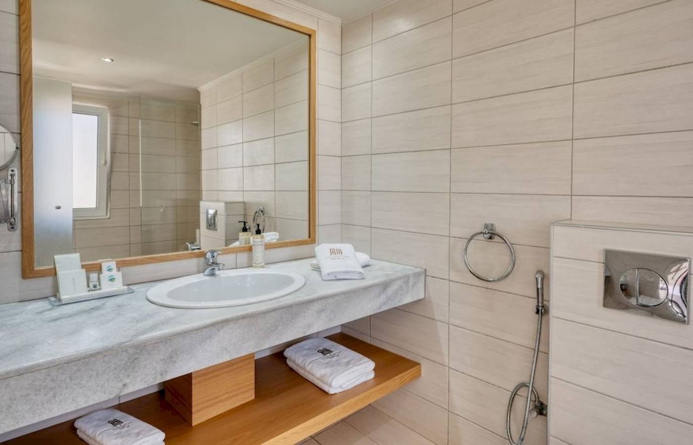 Badezimmer im Georgioupolis Resort Aquapark & SPA mit Marmorwaschbecken und Spiegel.