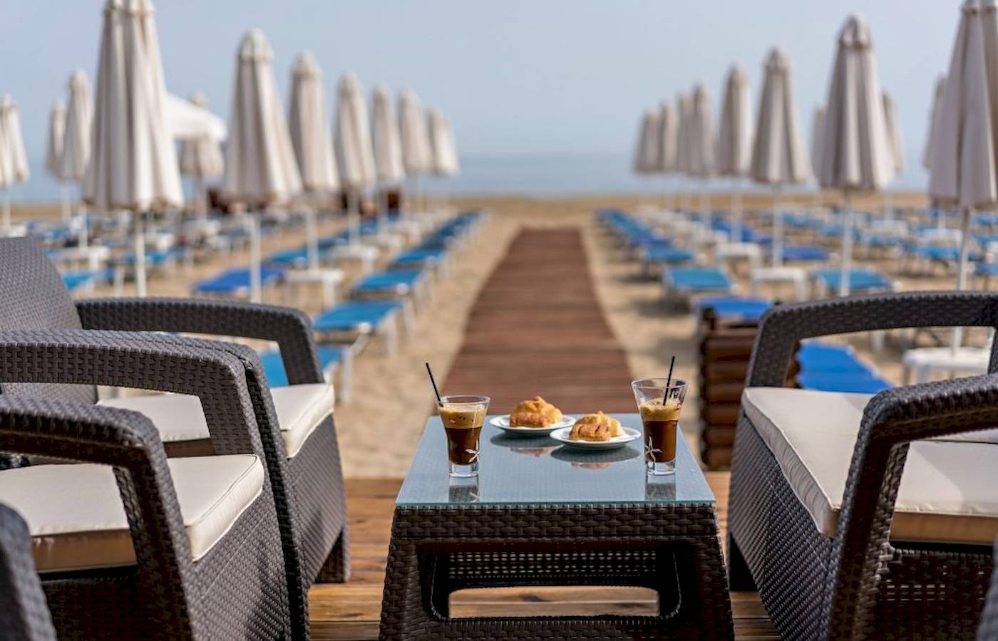 Georgioupolis Resort Aquapark & SPA Terrasse mit Tisch, Getränken und Sonneliegen.