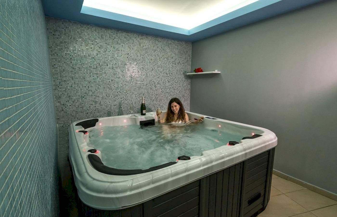 Frau im Jacuzzi im Georgioupolis Resort Aquapark & SPA mit einer Flasche und einem Glas.