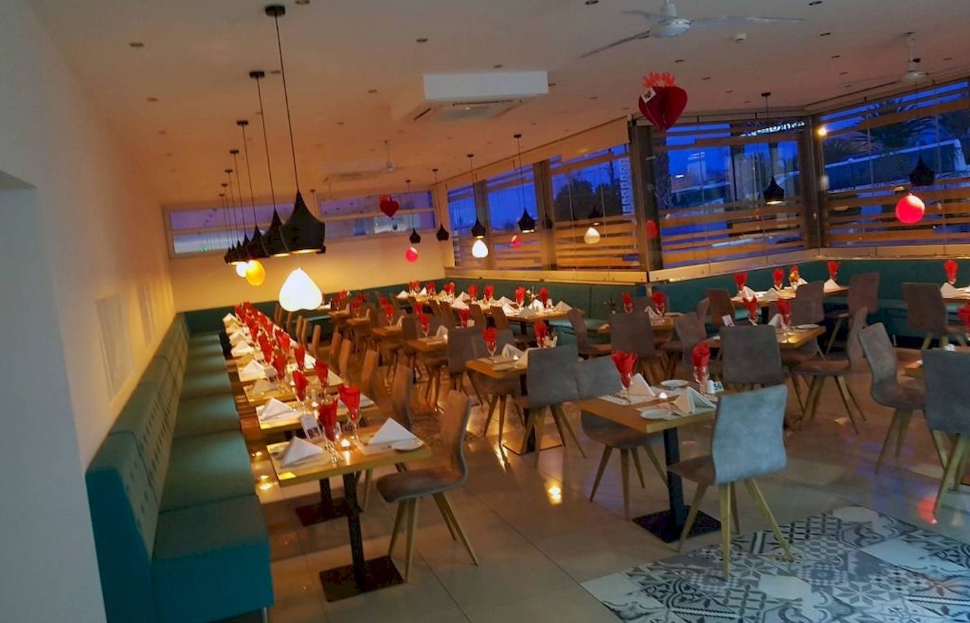 Innenbereich des Georgioupolis Resort Aquapark & SPA mit vielen gedeckten Tischen und roten Herzen an der Decke.