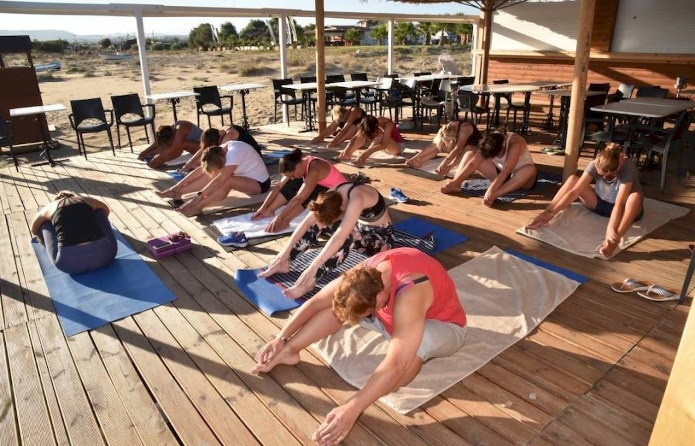 Mehrere Frauen und Männer machen Yoga auf einer Terrasse im Freien im Georgioupolis Resort Aquapark & SPA.