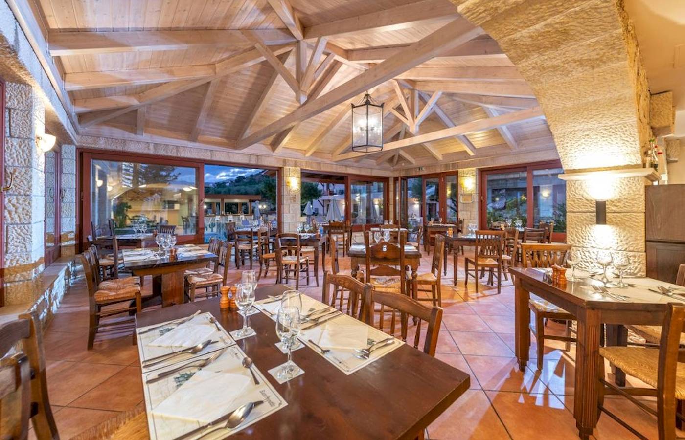 Innenbereich des Restaurants im Cactus Village Hotel & Bungalows mit Holztischen und Stühlen.