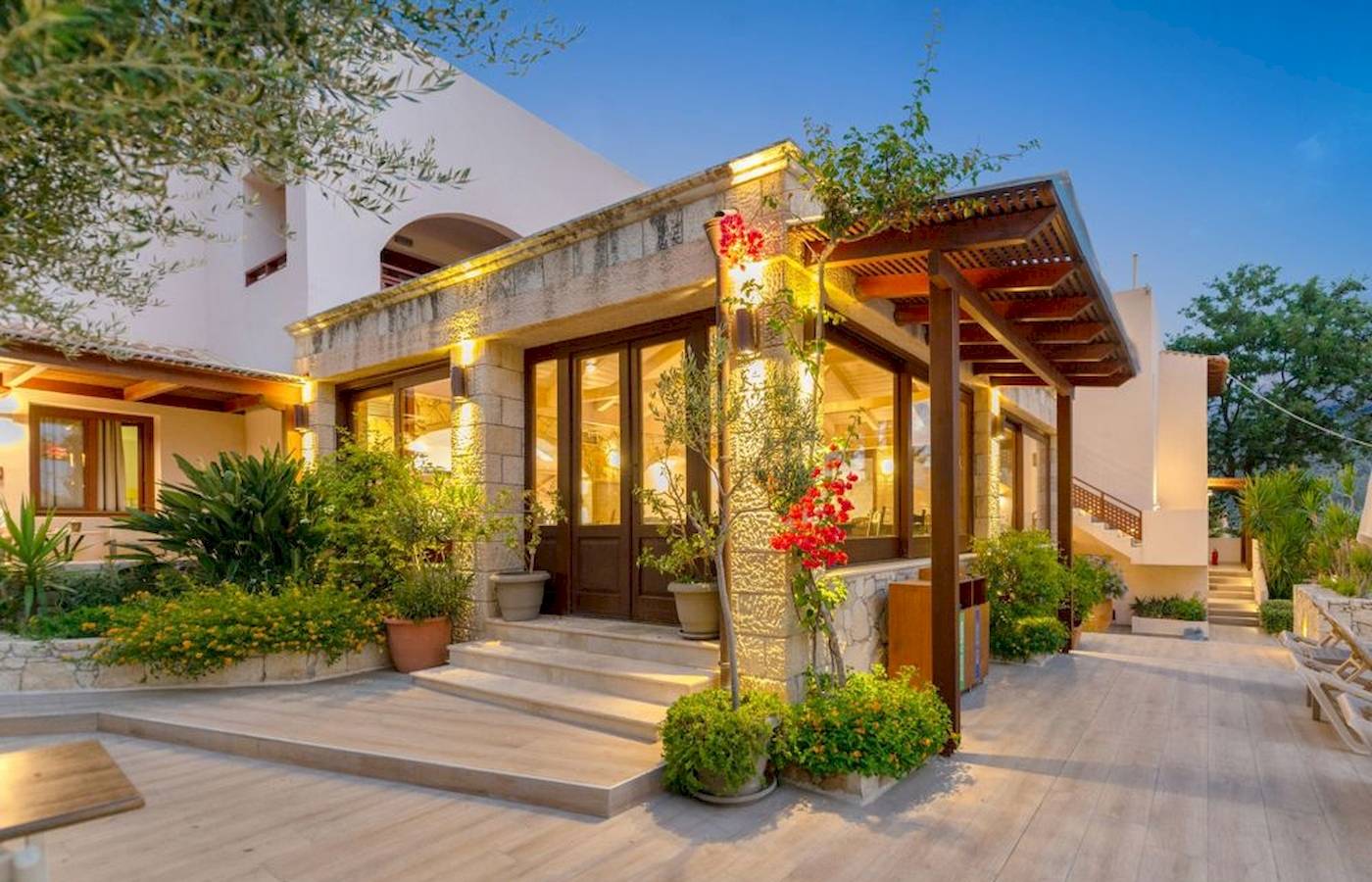 Außenansicht des Cactus Village Hotel & Bungalows mit gepflastertem Eingang und Pflanzen.