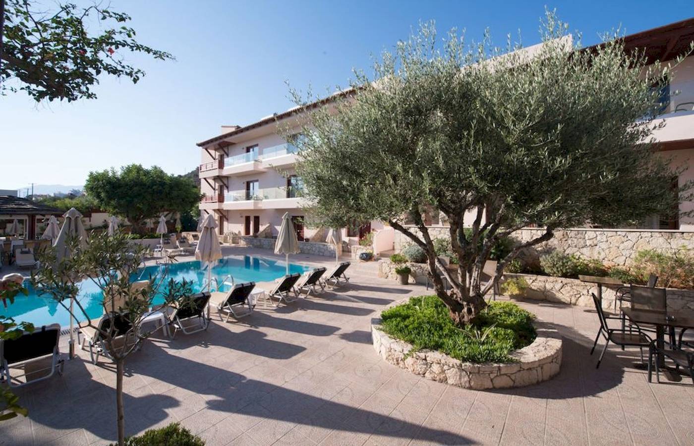 Pool-Lounge-Bereich des Cactus Village Hotel & Bungalows mit Liegen und Sonnenschirmen.