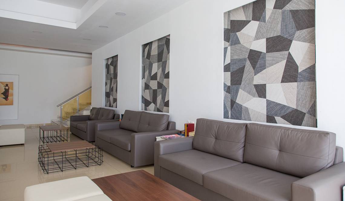 Loungebereich im Sun Palace Hotel mit grauen Ledersofas, geometrischen Wandteppichen und modernen Couchtischen.