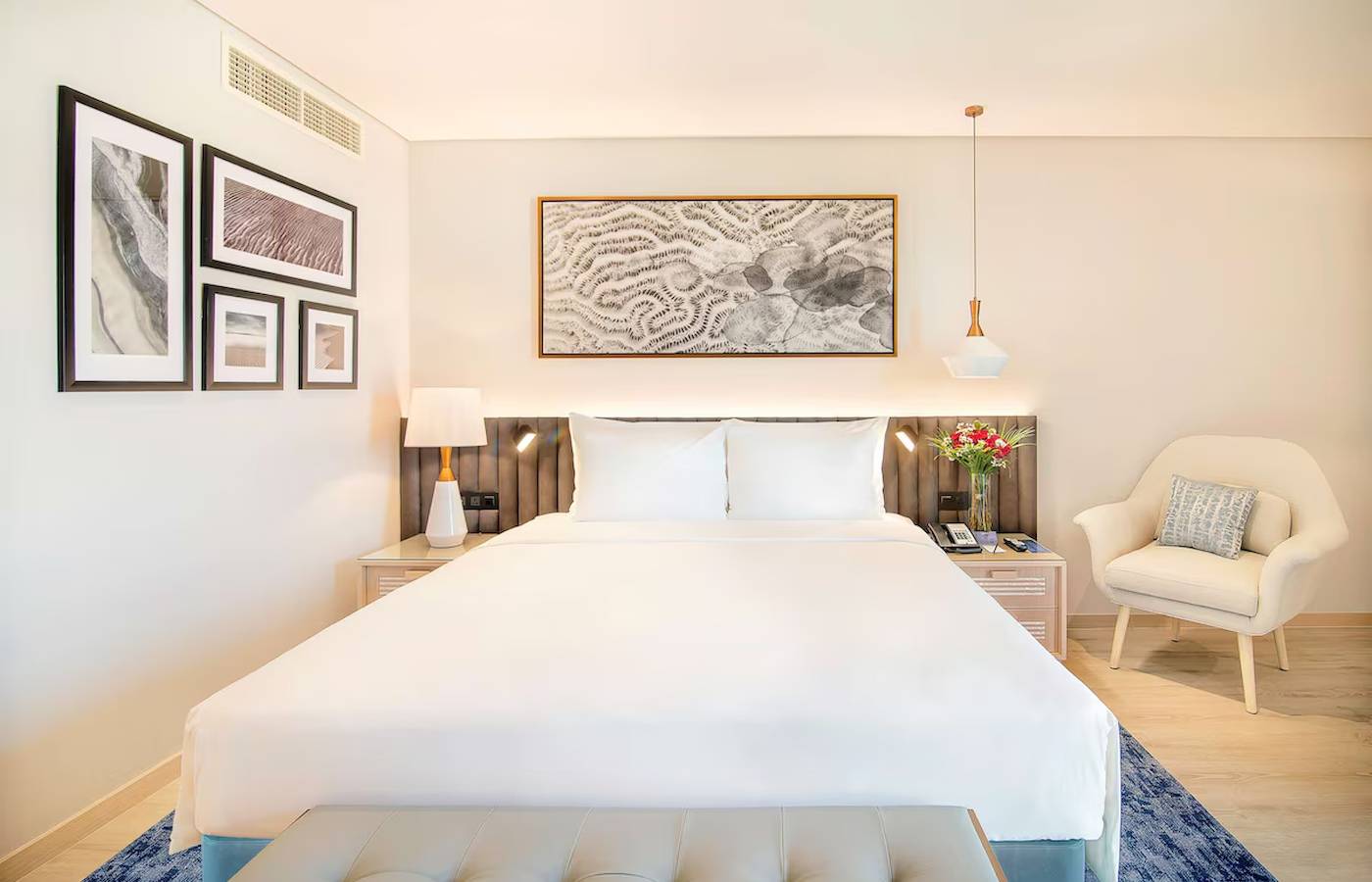 Innenansicht eines Schlafzimmers im Radisson Blu Hotel & Resort, Abu Dhabi Corniche, mit Bett, Nachttischen und Dekor.