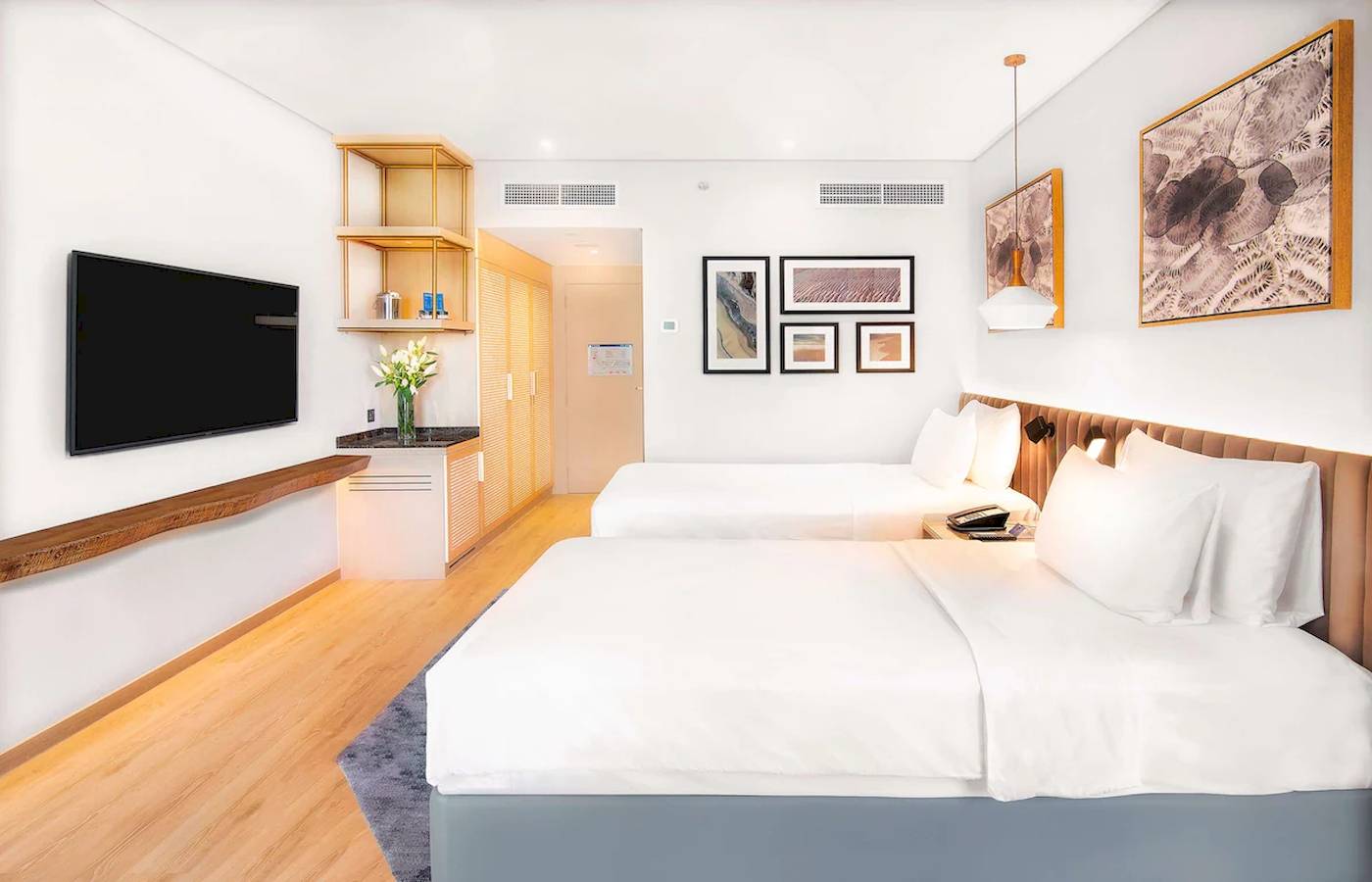 Innenansicht eines Zimmers im Radisson Blu Hotel mit zwei Betten, Fernseher und Kunstwerken an der Wand.