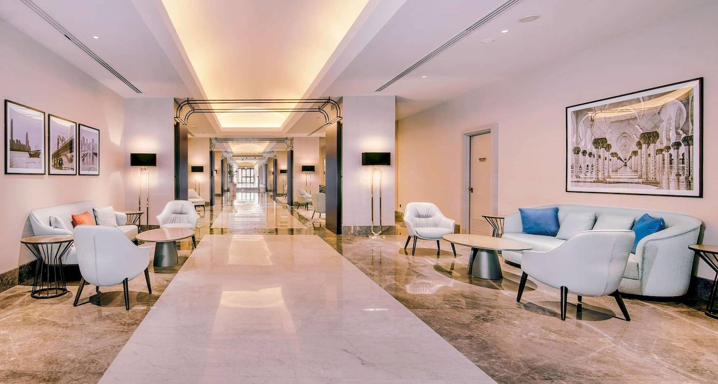 Lobby des Radisson Blu Hotel & Resort, Abu Dhabi Corniche mit weißen Möbeln und langen Flur