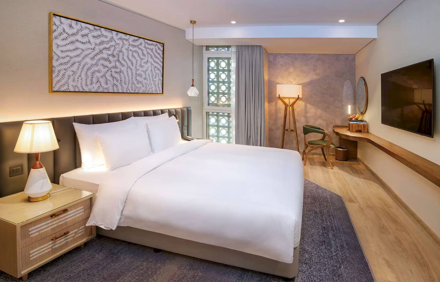 Das moderne Zimmer im Radisson Blu Hotel Abu Dhabi Corniche mit Bett, Lampen und Fernseher.