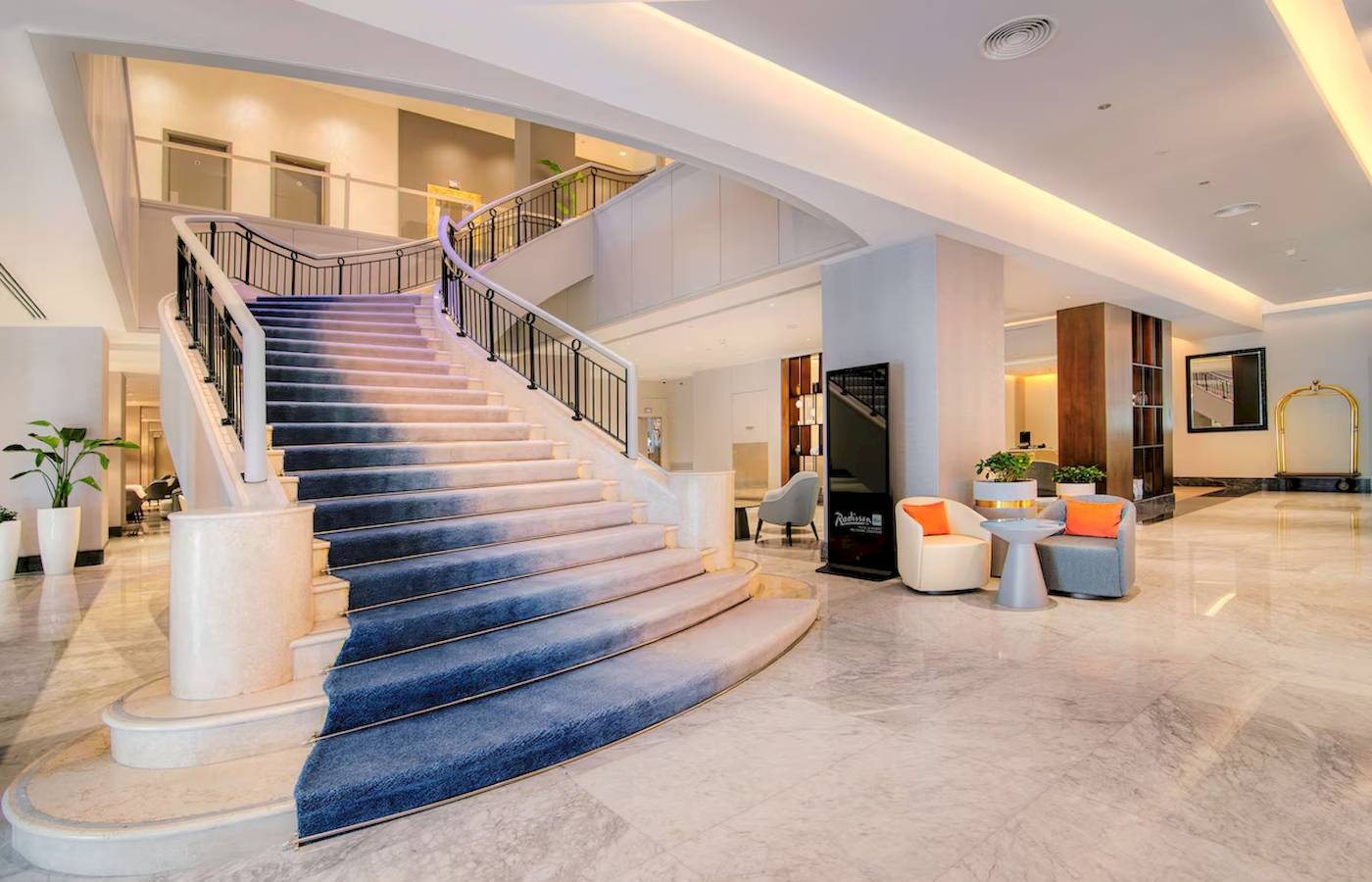 Lobbyansicht des Radisson Blu Hotel & Resort in Abu Dhabi Corniche mit einer großen Treppe und Möbeln.