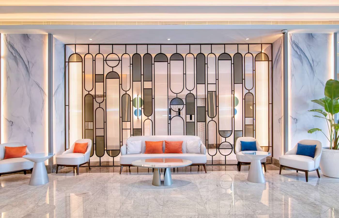 Das elegante Foyer des Radisson Blu Hotel & Resort in Abu Dhabi mit Marmorwänden und geometrischen Glaswänden.