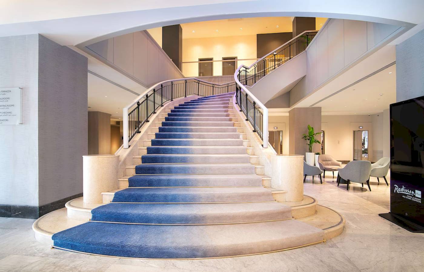 Treppenhaus im Radisson Blu Hotel & Resort, Abu Dhabi Corniche mit blauen Stufen und moderner Inneneinrichtung.
