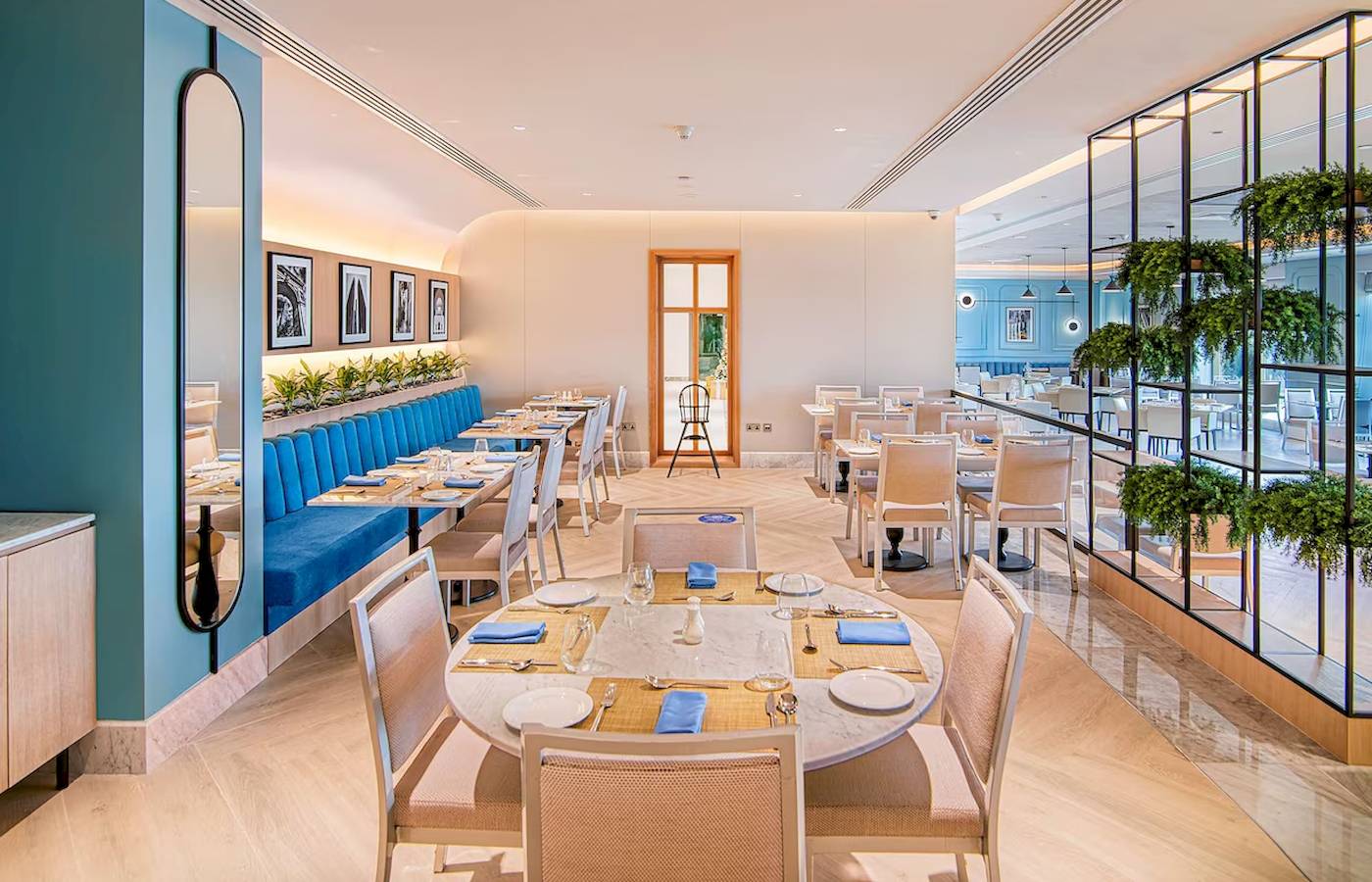 Innenansicht des Restaurants im Radisson Blu Hotel & Resort, Abu Dhabi Corniche mit blauen Sitzbänken und Tischdecken.