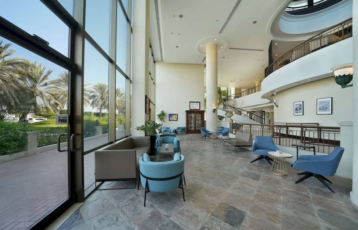 Lobby des Radisson Blu Hotels & Resort in Abu Dhabi mit blauen Stühlen und Tischen.