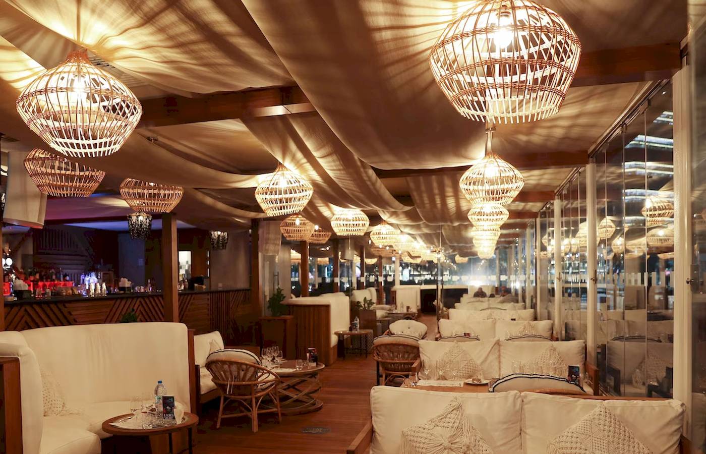 Innenansicht des Restaurants im Radisson Blu Hotel mit weißen Sofas und Rattan-Stuhl in Abu Dhabi Corniche.