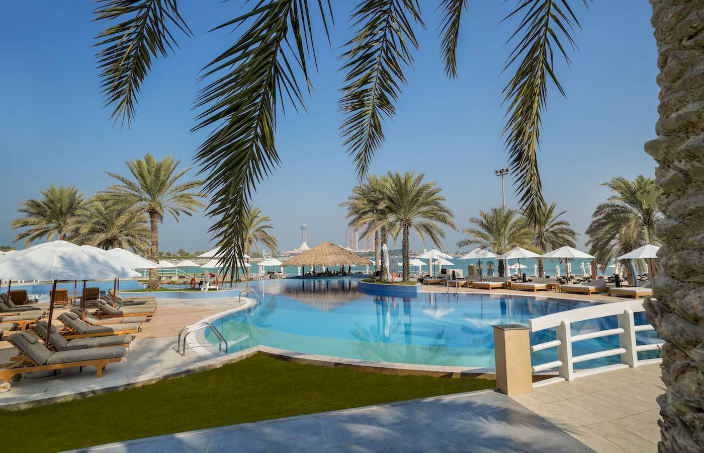 Außenpool des Radisson Blu Hotel & Resort in Abu Dhabi mit Liegestühlen und Sonnenschirmen.