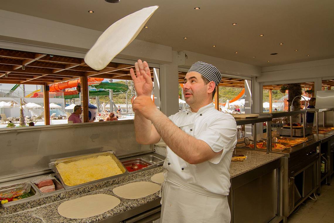 Koch im Sun Palace Hotel wirft Pizza-Teig in die Luft.