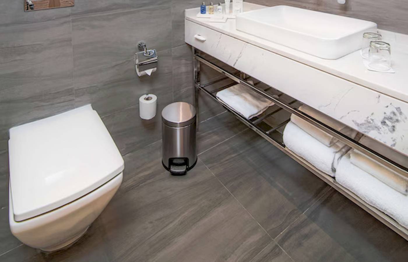 Badezimmer im Radisson Blu Hotel & Resort, Abu Dhabi Corniche mit grauen Wänden, Marmor-Waschtisch und Toilette.