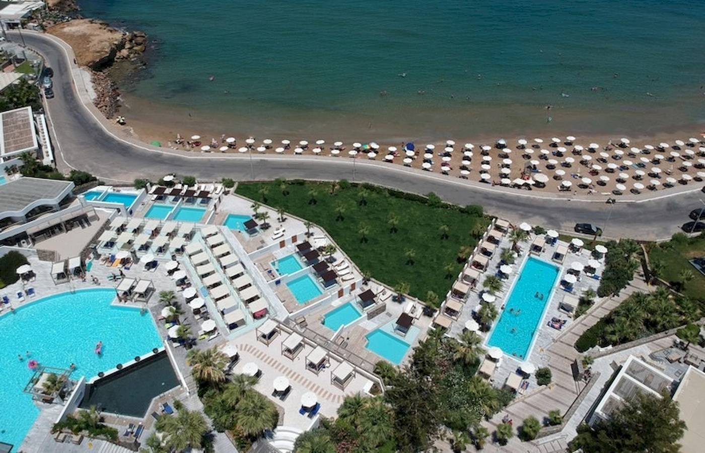 Oberflächenansicht des The Island Hotel auf Kreta mit mehreren Swimmingpools, Liegen und Sonnenschirmen.