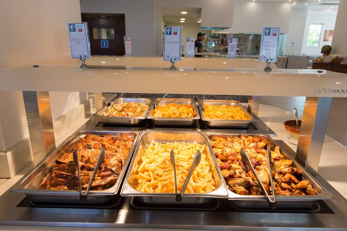Buffet-Tisch im Sun Palace Hotel mit verschiedenen Speisen wie BBQ-Ribs, French Fries, gratiniertem Käse und gebratenem Fleisch.