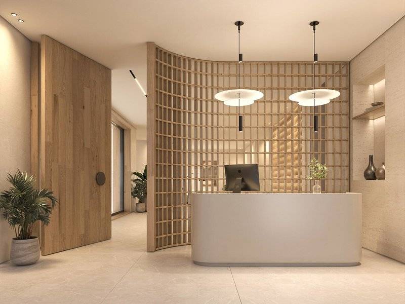 Innenansicht der Rezeption im Jaz Elite Amara Hotel mit weißem Tresen, Holzwand und Pflanzen.
