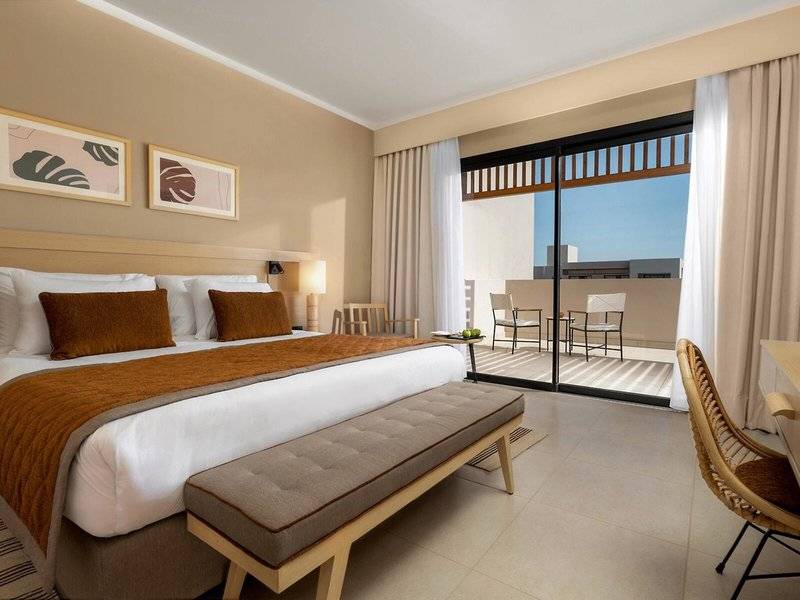 Hotelzimmer im Jaz Elite Amara mit großem Bett, Balkon und Stadtblick.