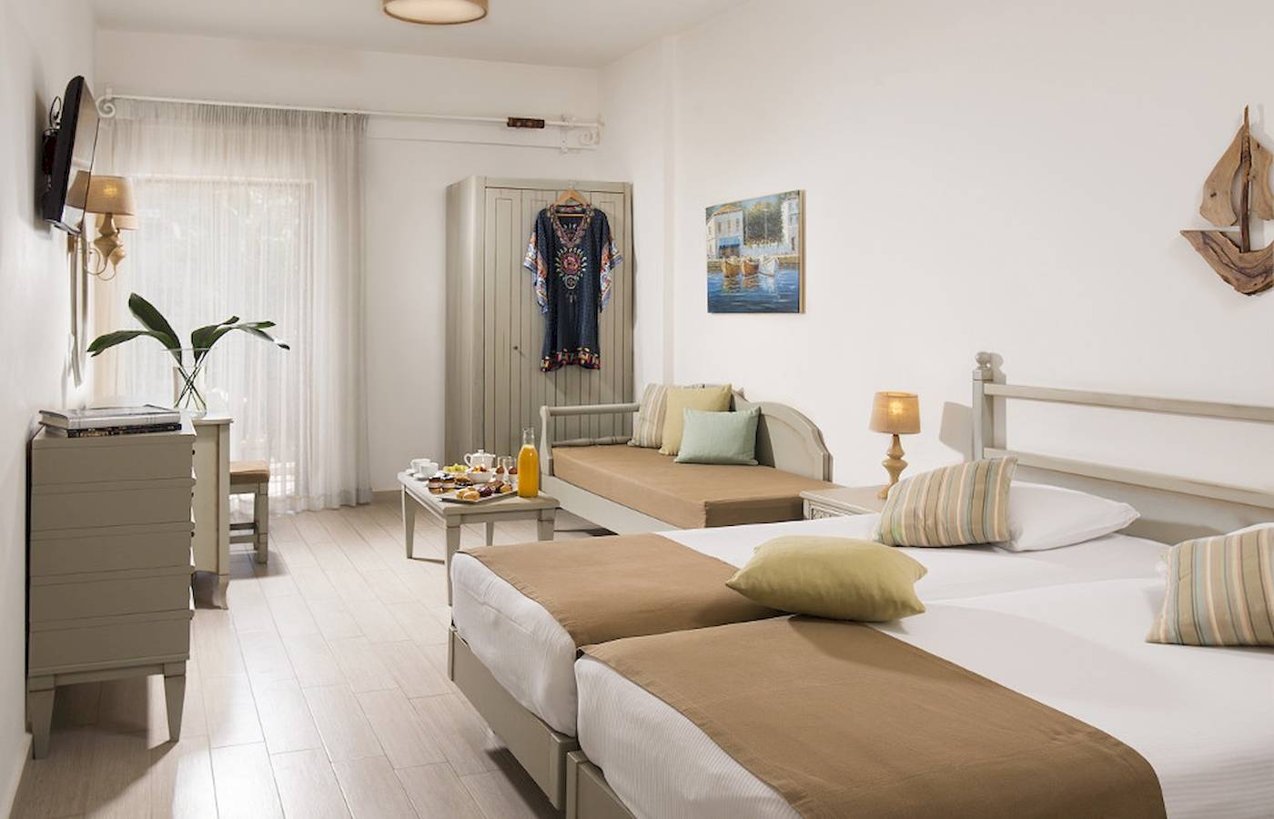 Doppelzimmer im Almyrida Beach Hotel mit zwei Betten, Tisch und Dekoration.