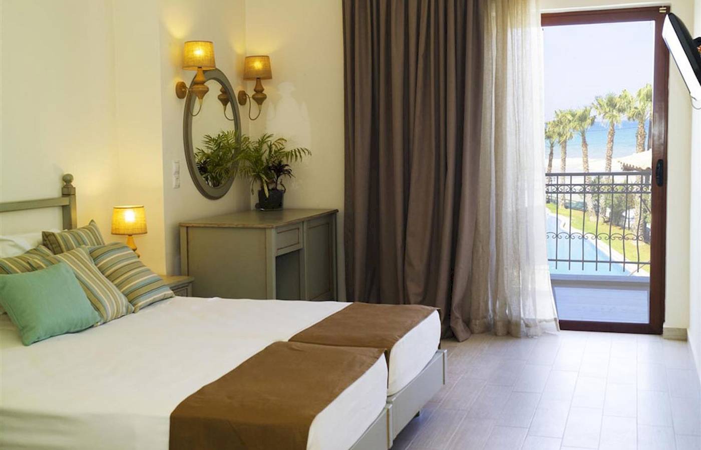 Doppelzimmer im Almyrida Beach Hotel mit Blick auf den Pool und die Palmen.