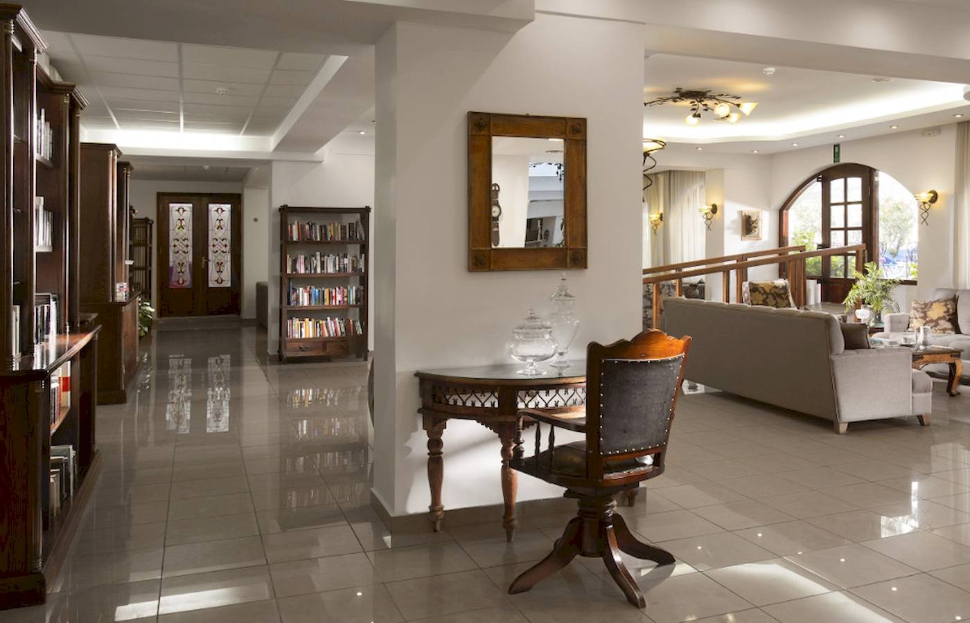 Empfangsbereich des Almyrida Beach Hotels mit gefliestem Boden, Couch, Tisch und Bücherregal.