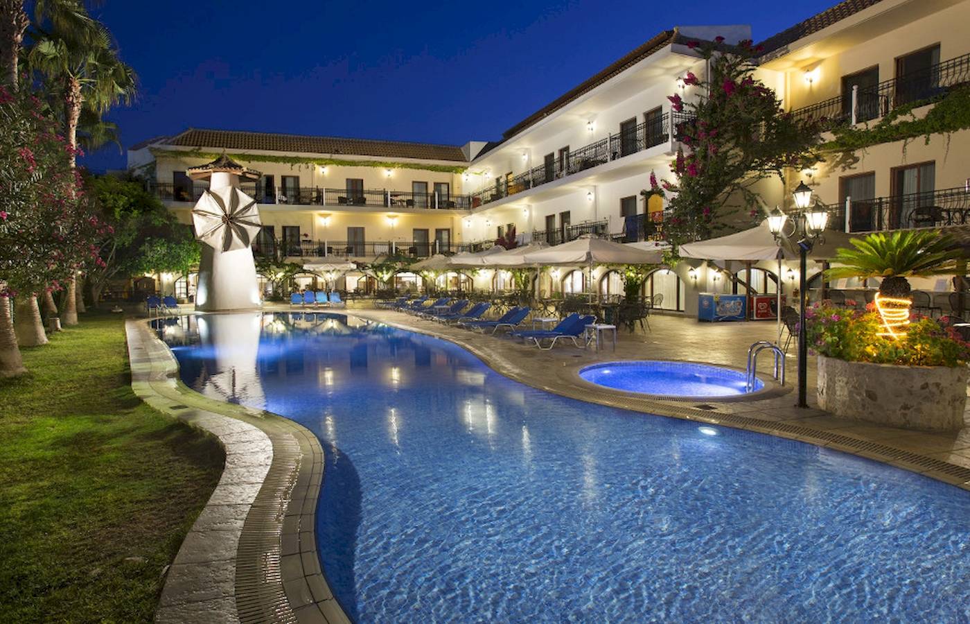 Almyrida Beach Hotel Pool am Abend mit Lounge-Sesseln und beleuchteten Gebäuden