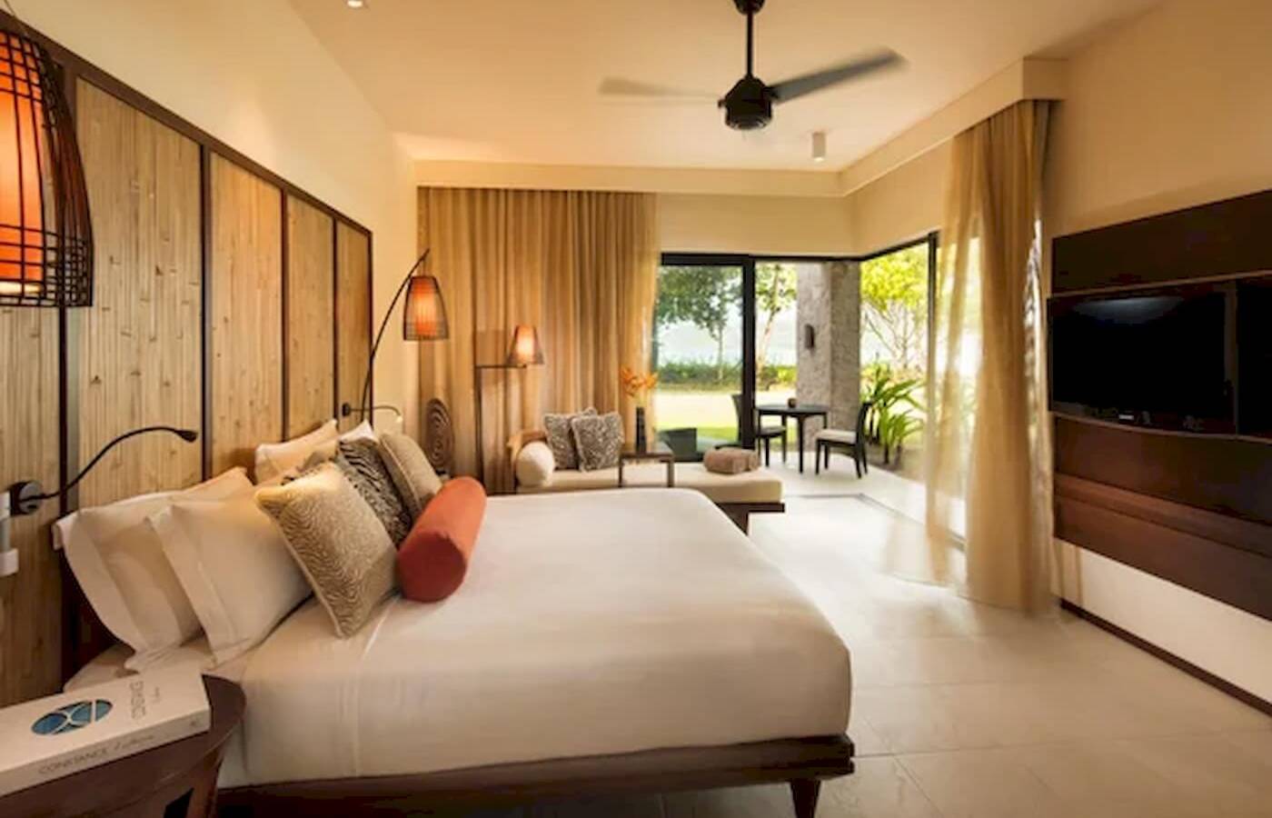 Schlafzimmer im Constance Ephelia Resort mit großem Bett, Fenstern und Blick auf die Terrasse.