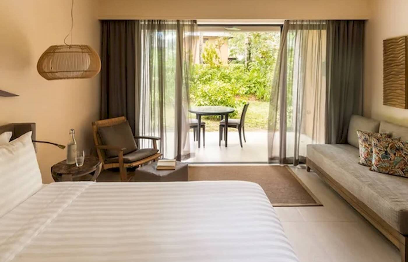 Schlafzimmer im Constance Ephelia Resort mit Blick auf den Garten und einem Tisch mit Stühlen.