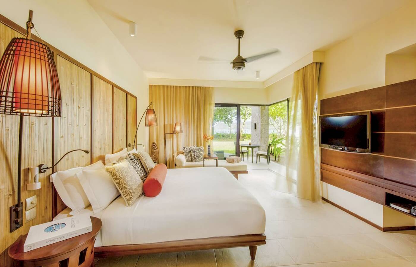 Schlafzimmer im Constance Ephelia Resort mit großem Bett, Dekokissen und Fernseher.