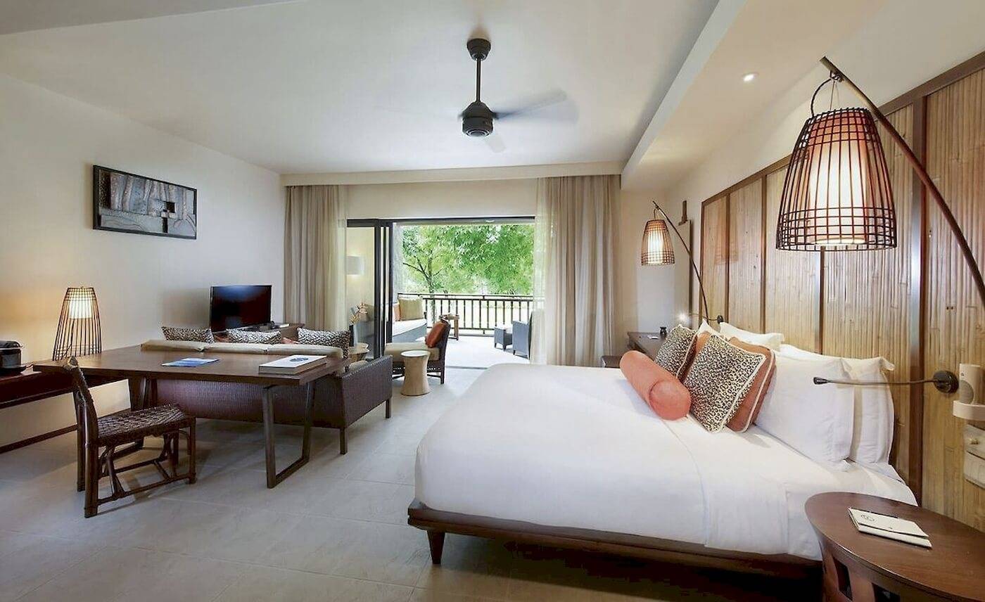 Schlafzimmer im Constance Ephelia Resort mit großem Bett, Schreibtisch und Balkon.