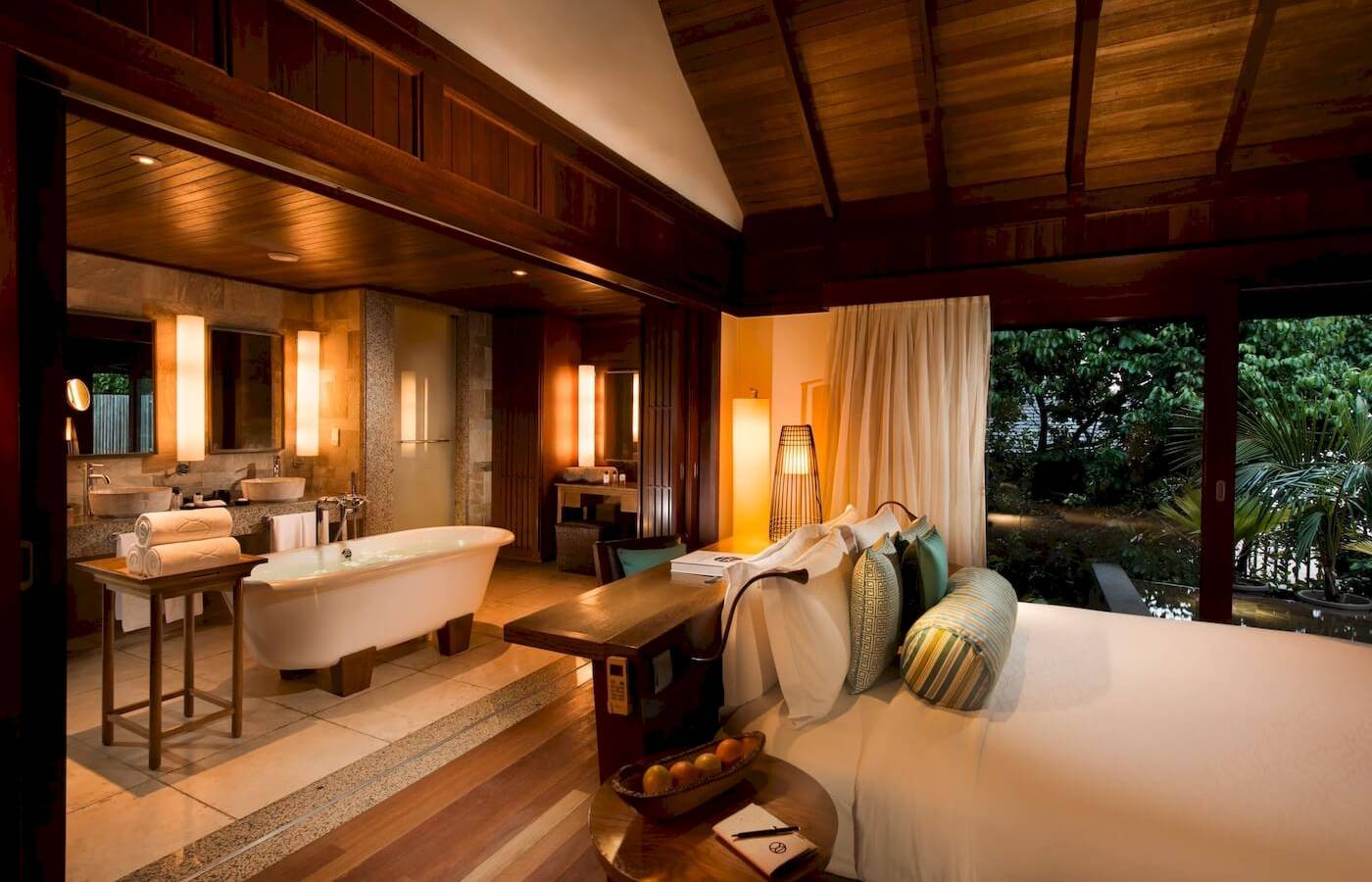 Innenansicht eines Luxus-Schlafzimmers im Constance Ephelia Resort mit Badewanne, Bett und offenem Fenster.