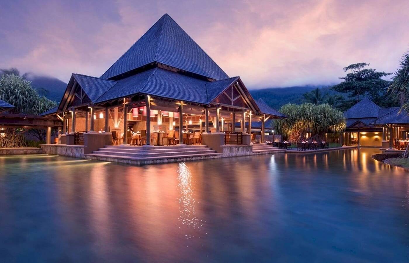 Nachtansicht des Constance Ephelia Resorts mit blauem Dach und Pool