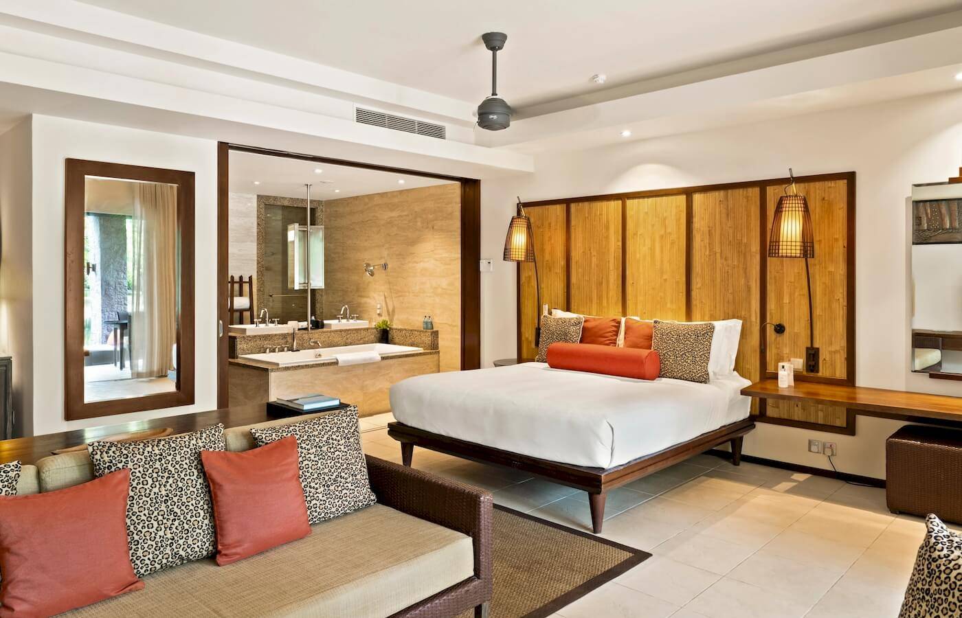 Innenansicht der Luxus-Suite im Constance Ephelia Resort mit Bett, Sofa und Badezimmer.