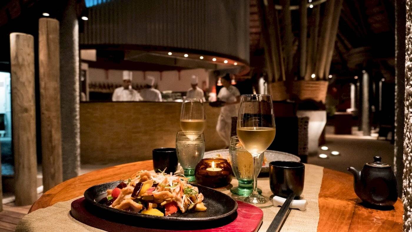 Foto von einem Tisch im Constance Ephelia Resort mit Speisen, Getränken und Kellnern im Hintergrund.