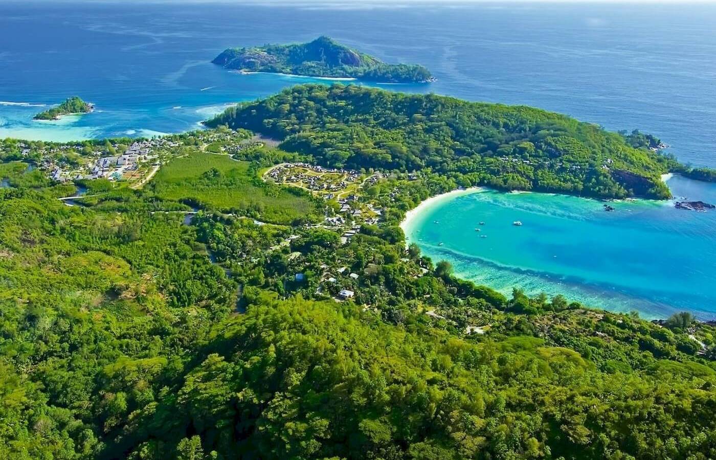 Luftaufnahme des Constance Ephelia Resorts auf einer Insel mit türkisfarbenem Wasser und grüner Vegetation.