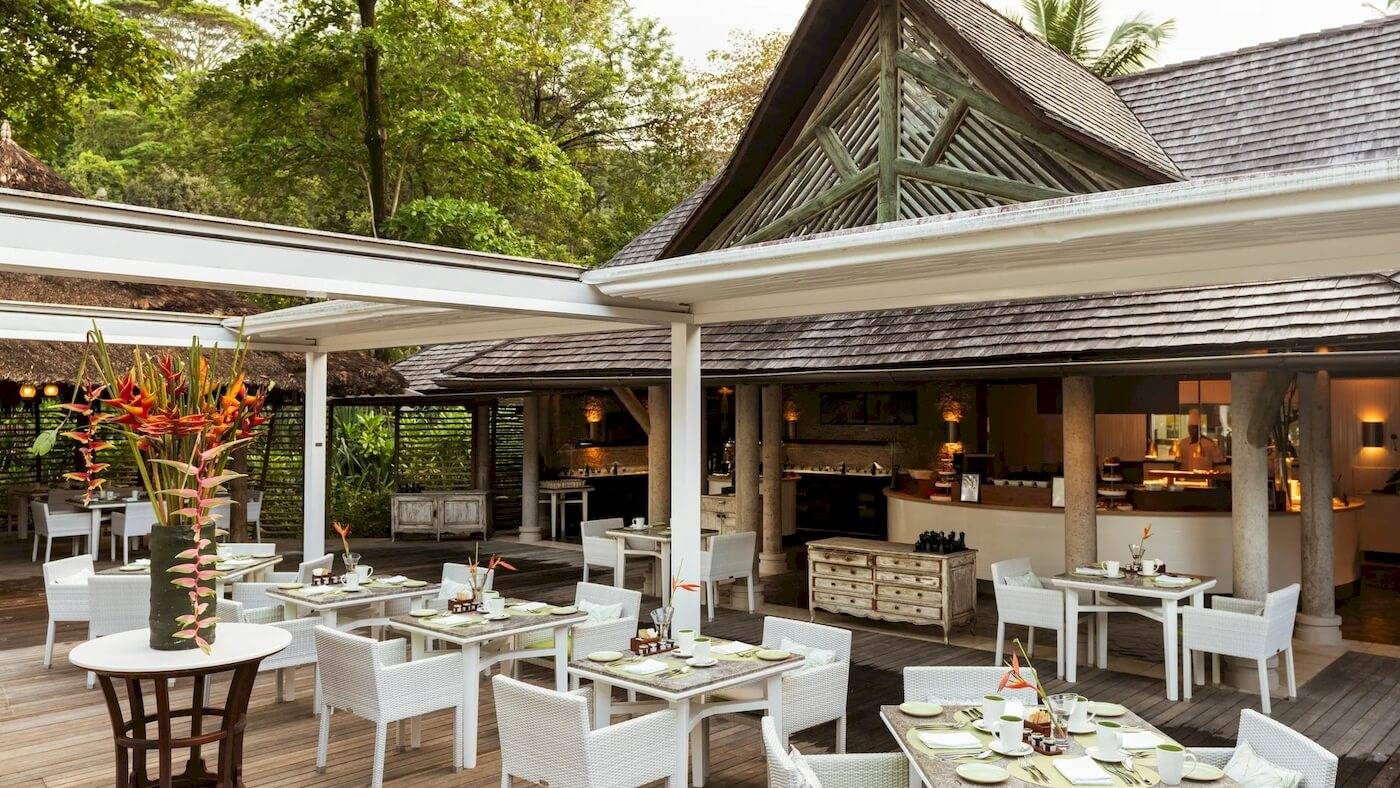 Außenbereich des Constance Ephelia Resorts mit Tisch und Stühlen, umgeben von Pflanzen.