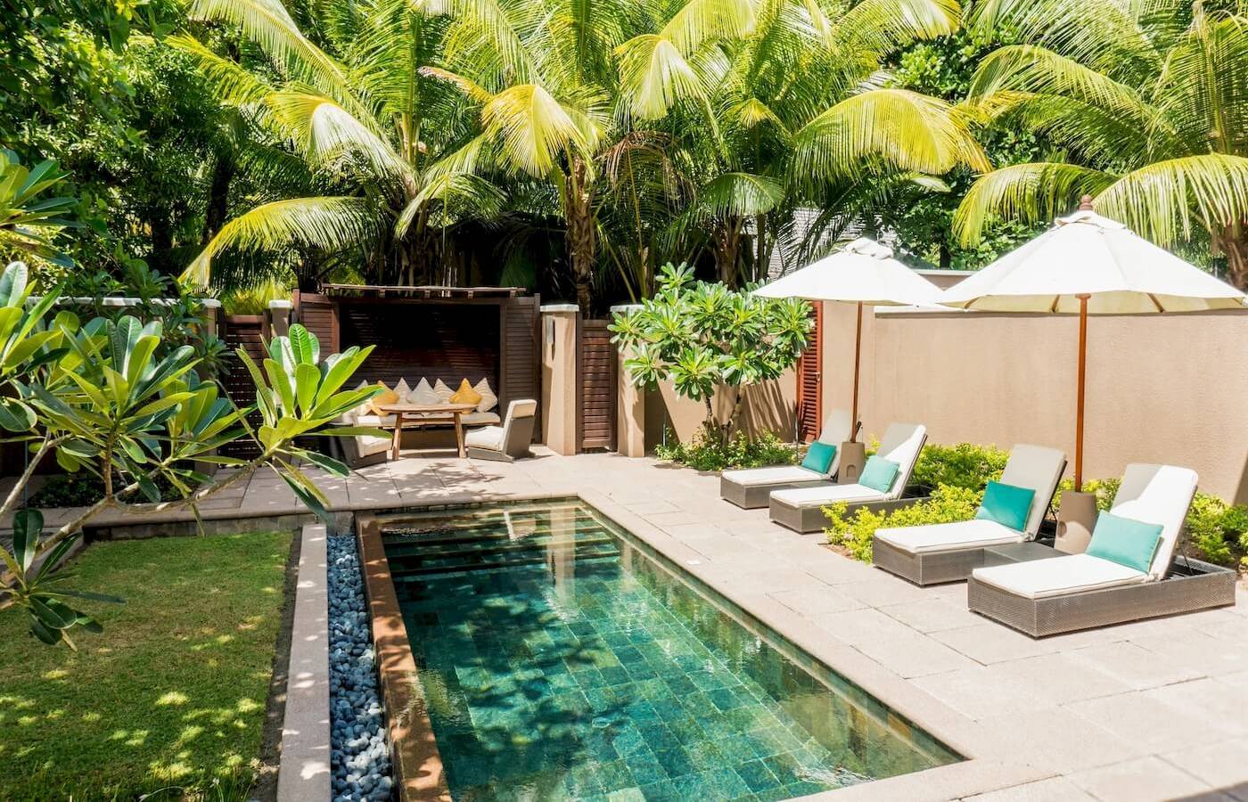 Außenbereich des Constance Ephelia Resorts mit Pool, Liegestühlen und Sonnenschirmen.