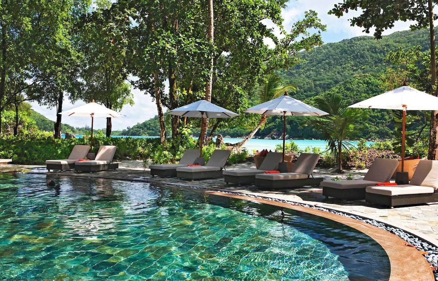 Außenpool mit Lounge-Sesseln und Sonnenschirmen im Constance Ephelia Resort.