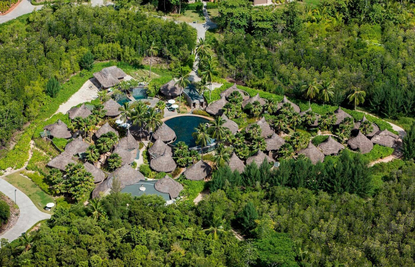 Luftaufnahme des Constance Ephelia Resorts mit tropischen Bungalows und Pools inmitten grüner Vegetation.