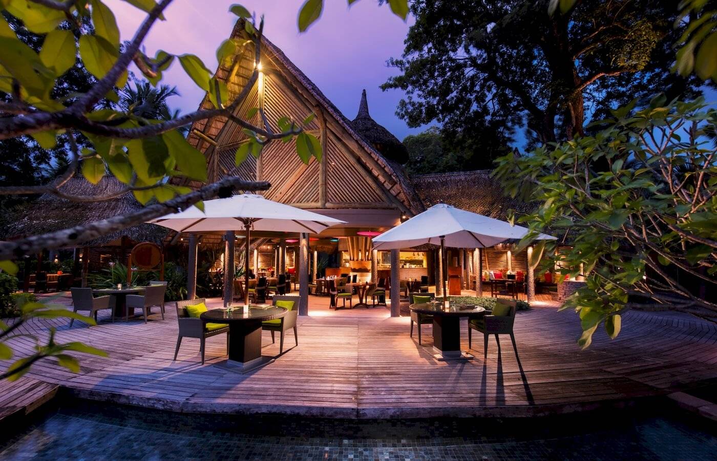 Terrasse des Constance Ephelia Resorts bei Nacht mit beleuchteten Tischen und Stühlen.