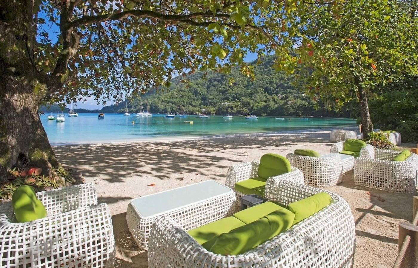 Lounge-Set am Strand des Constance Ephelia Resorts mit Blick auf das Meer und Berge.