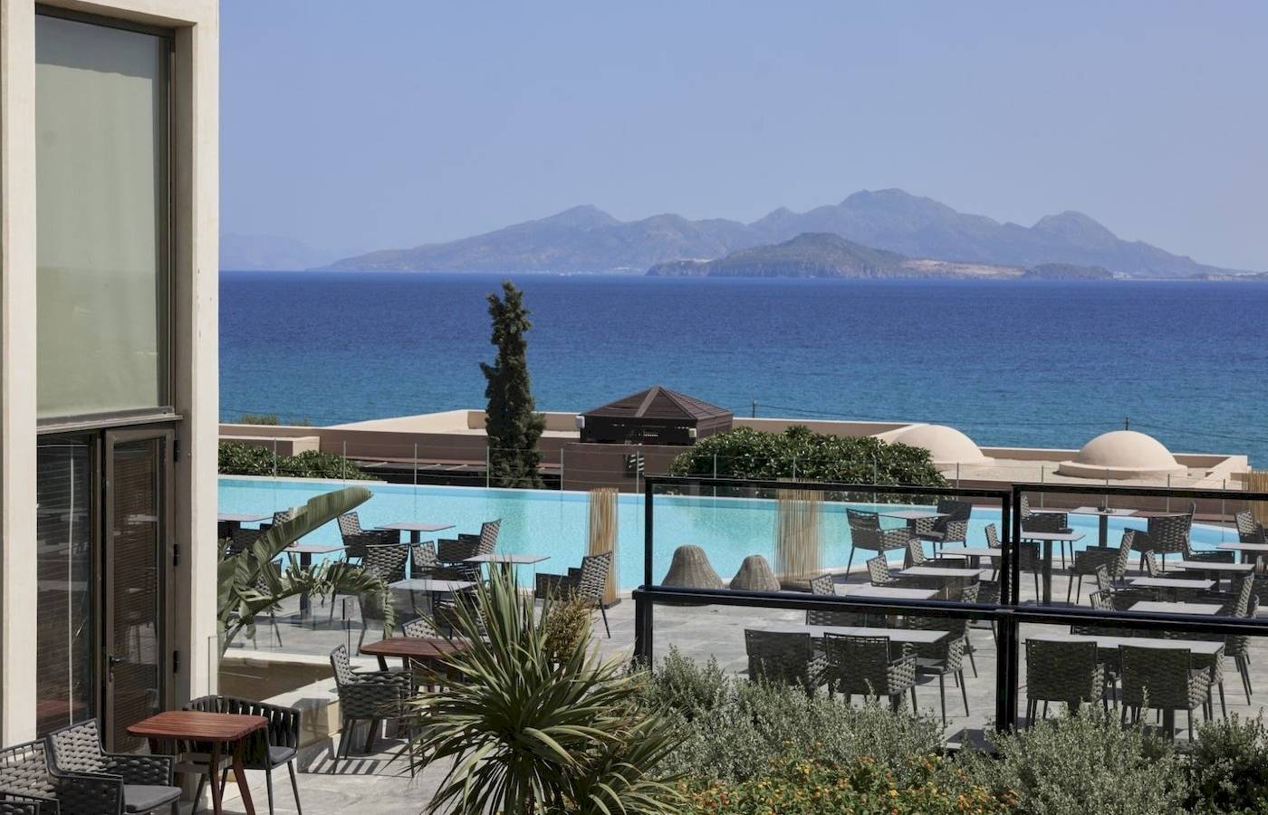 Außenbereich des Atlantica Beach Resort Kos mit Blick auf den Pool und die Berge.