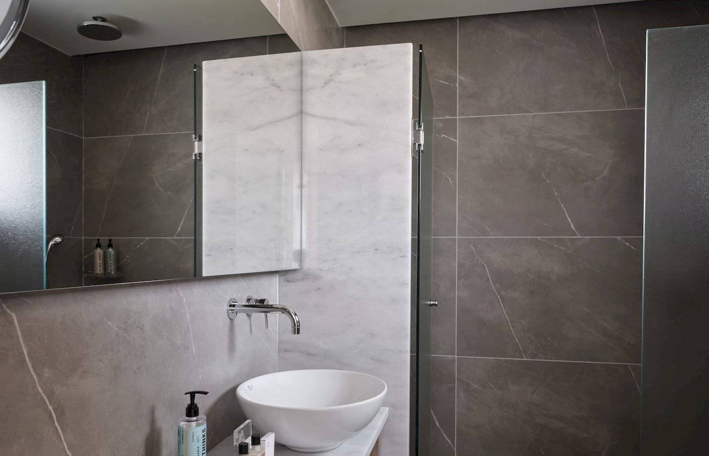 Badezimmer im Atlantica Beach Resort Kos mit grauen und weißen Fliesen und einem weißen Waschbecken.