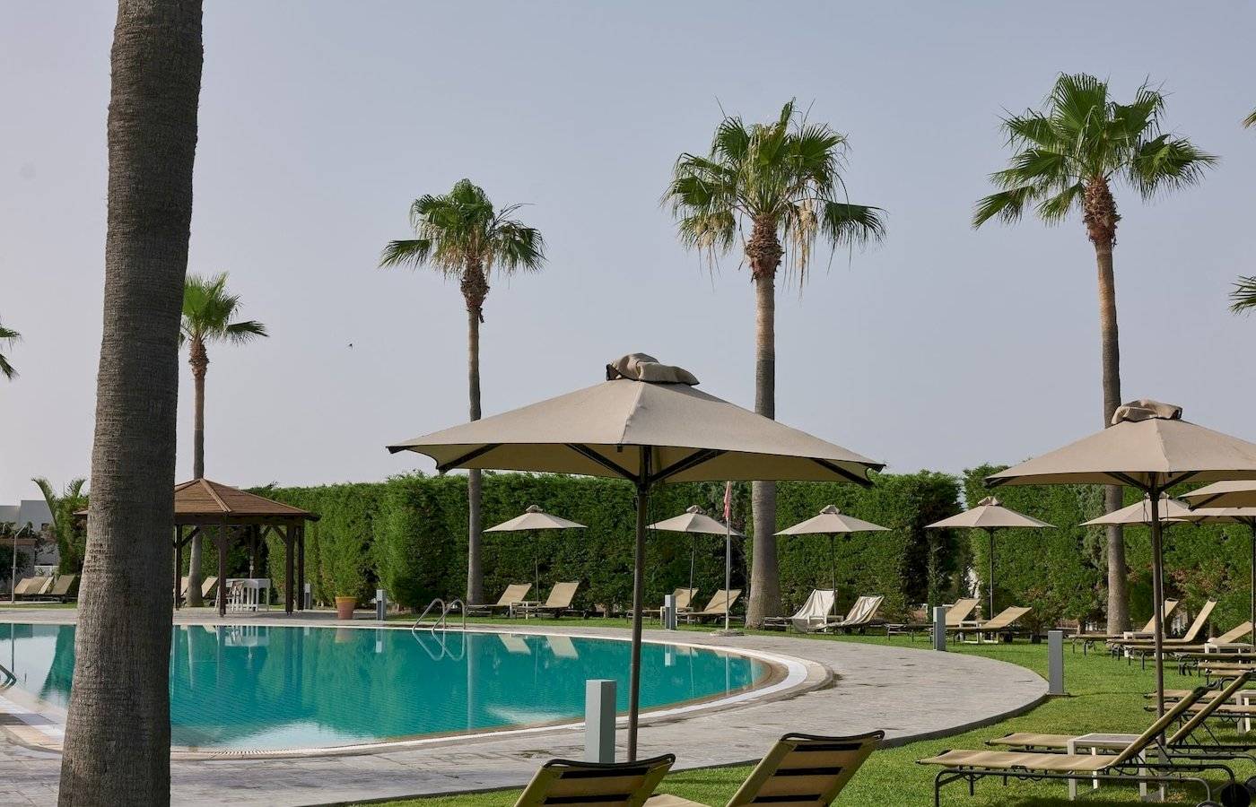 Poolbereich des Atlantica Beach Resort Kos mit Sonnenliegen und Sonnenschirmen.