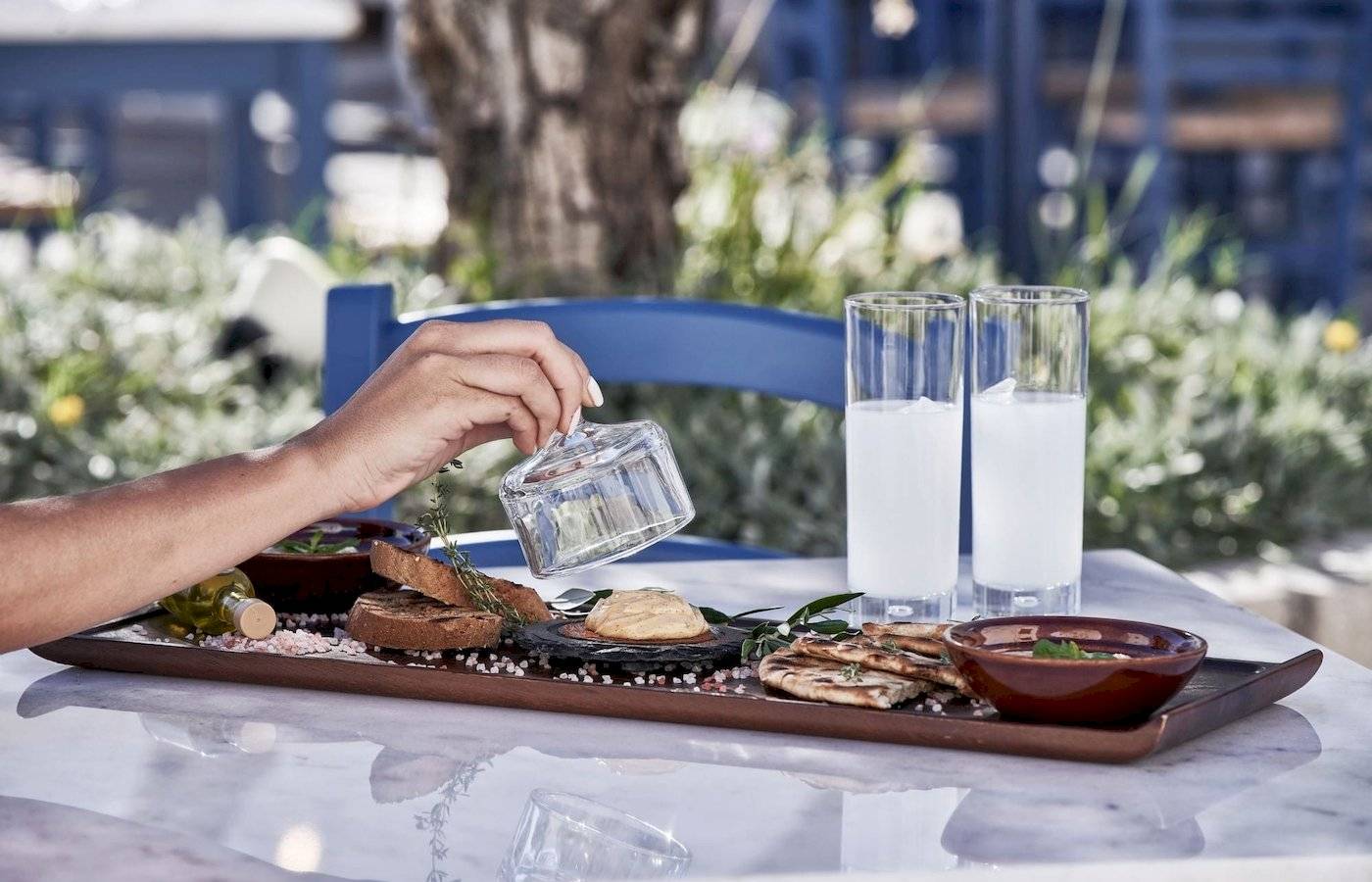 Frühstücksplatte im Atlantica Beach Resort Kos mit Brot, Olivenöl, Dip und Getränken.